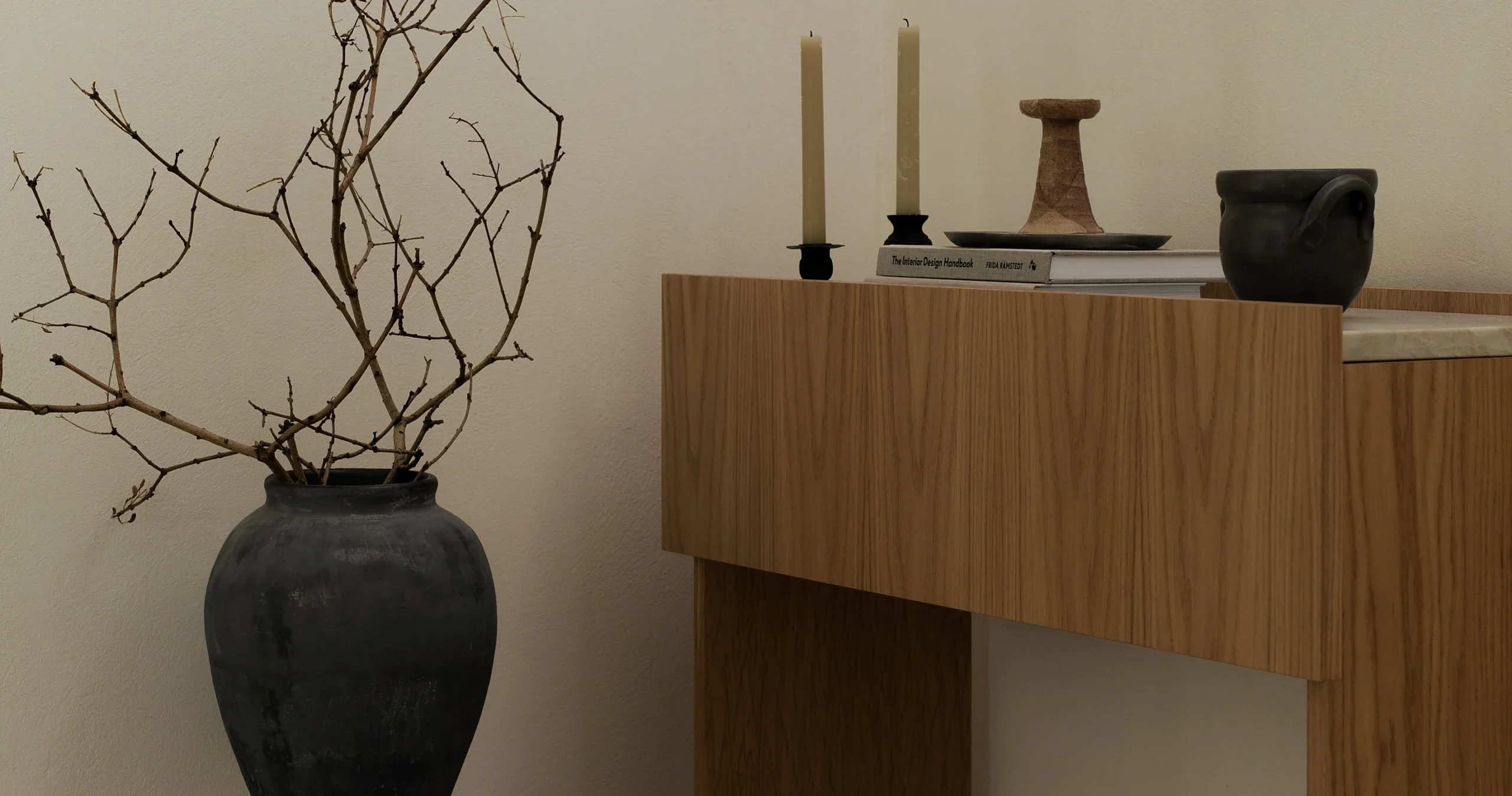 Vase de branches et objets sculpturaux dans un intérieur neutre