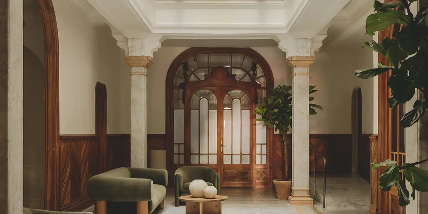 Le hall de Casa Llimona : colonnes en marbre, porte en arche et fauteuils verts