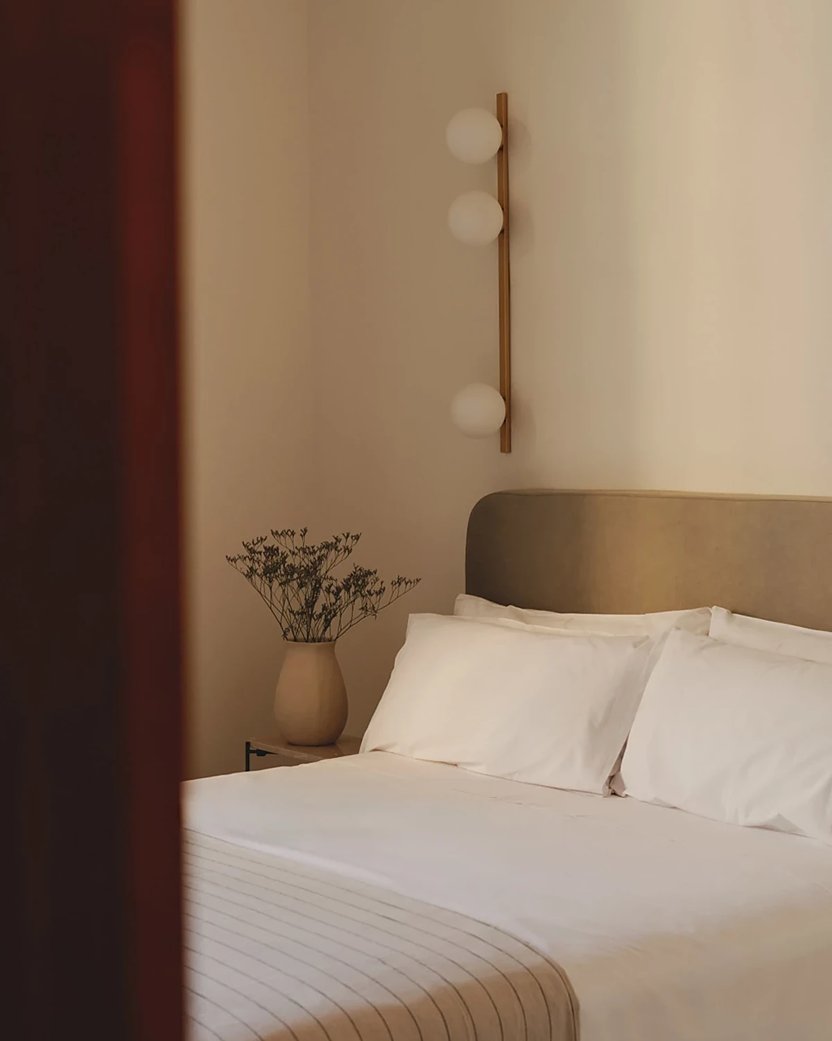 Chambre de Casa Llimona : lit, tête de lit en tissu et applique murale