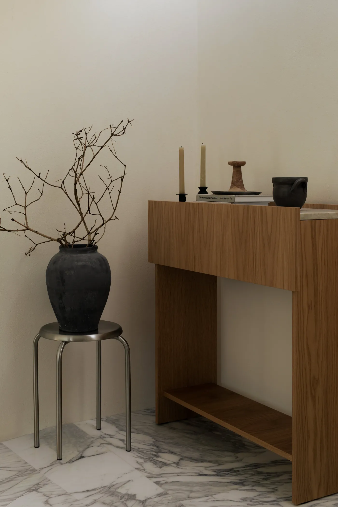 Vase de branches sur un tabouret, console en bois et bougies